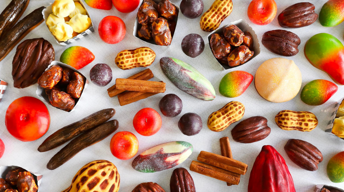 Assortimento di "Fruits Sculptés" di Cédric Grolet, inclusi mango, arachidi, mele e fave di cacao.
