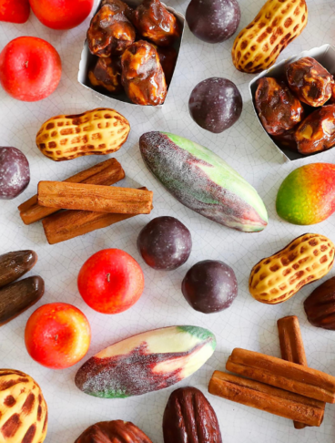 Assortimento di "Fruits Sculptés" di Cédric Grolet, inclusi mango, arachidi, mele e fave di cacao.