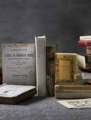 Una pila di libri di cucina di diverse epoche su un tavolo