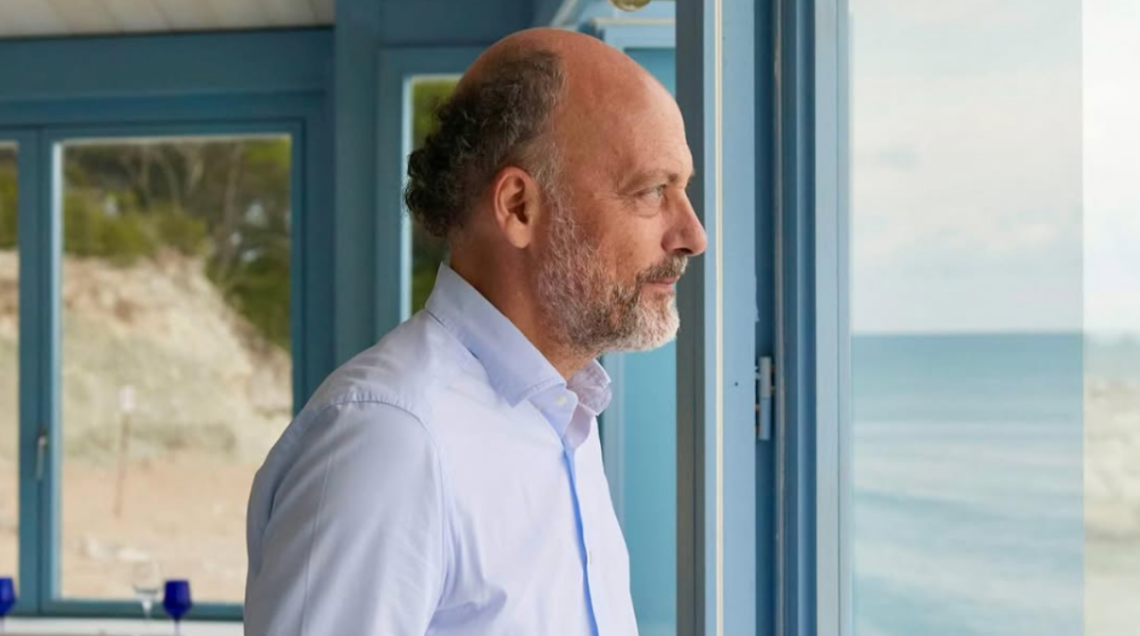 Lo chef Moreno Cedroni osserva il mare da una vetrata.