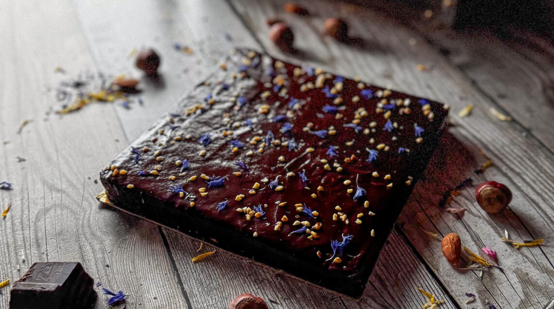 torta quadrata alle carote con glassa al cioccolato, decorata con granella di nocciole e fiori