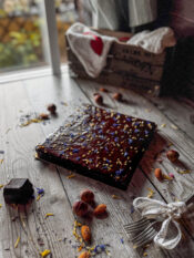 torta quadrata alle carote con glassa al cioccolato, decorata con granella di nocciole e fiori