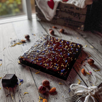 torta quadrata alle carote con glassa al cioccolato, decorata con granella di nocciole e fiori