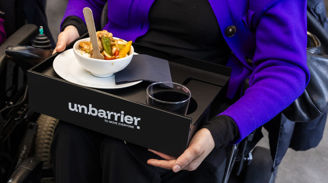 persona in carrozzina con vassoio con cibo e bevanda