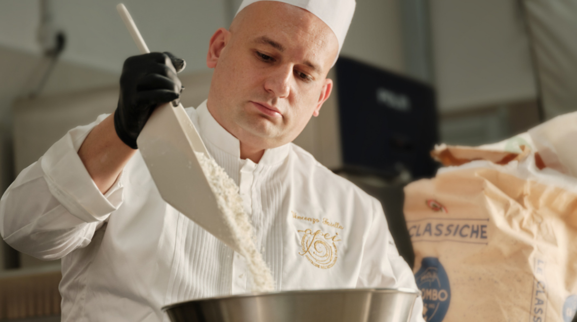 Il maestro pasticcere Vincenzo Faiella mentre versa ingredienti in una ciotola di acciaio.
