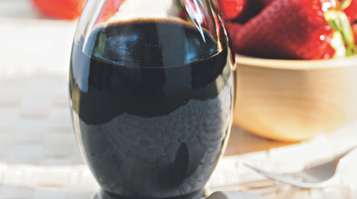 Bottiglietta di Aceto Balsamico Tradizionale di Modena DOP versato su fragole fresche