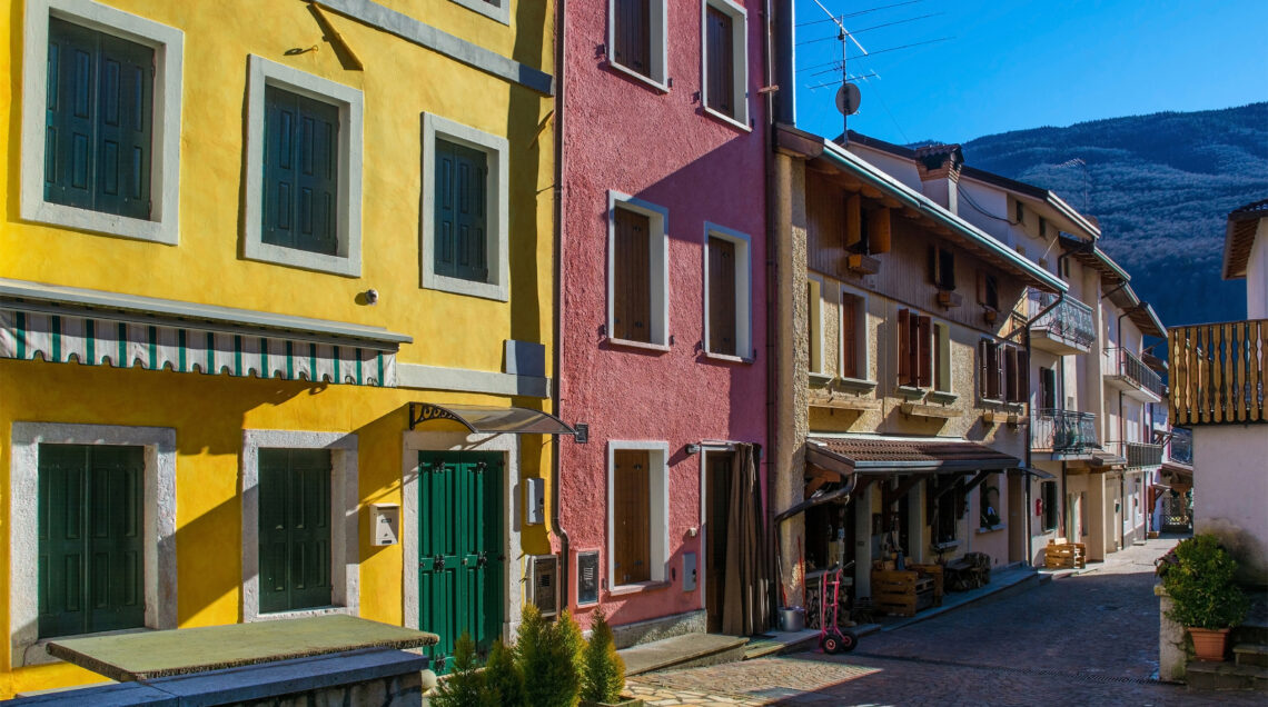 Case affiancate con facciate colorate in giallo e rosa nel centro di Barcis. 