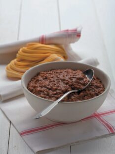 Una ciotola di ragù accanto a matassine di tagliatelle