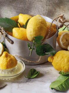limoni interi, tagliati e spremuti su un tavolo e in una pentola