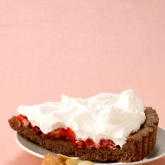 fetta di crostata con frolla al cacao, fragole e panna