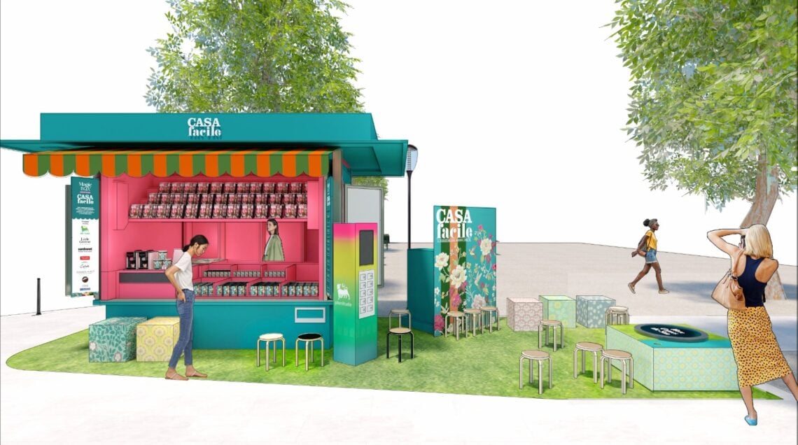 Rendering architettonico di un'edicola pop-up color verde ottanio con scaffali rosa e area relax esterna su prato sintetico.