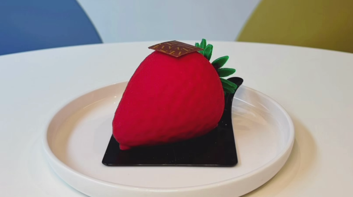 Dolce monoporzione a forma di fragola gigante con finitura effetto velluto rosso e picciolo in cioccolato.