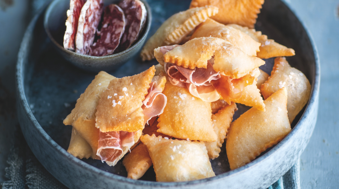 Vassoio di gnocco fritto caldo farcito con fette di prosciutto crudo e salame.