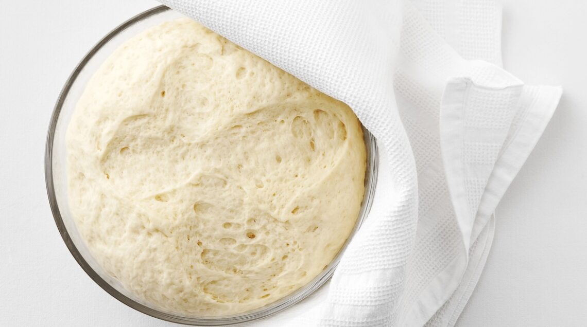 impasto lievitato in una ciotola con telo bianco