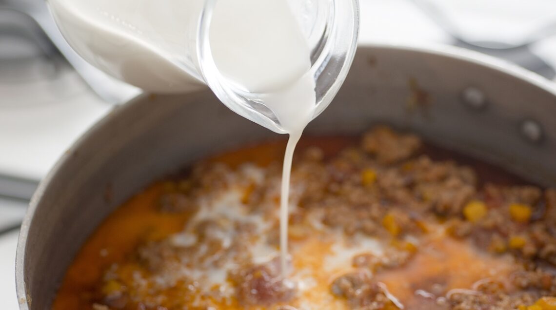 latte aggiunto a filo a un ragù sul fuoco