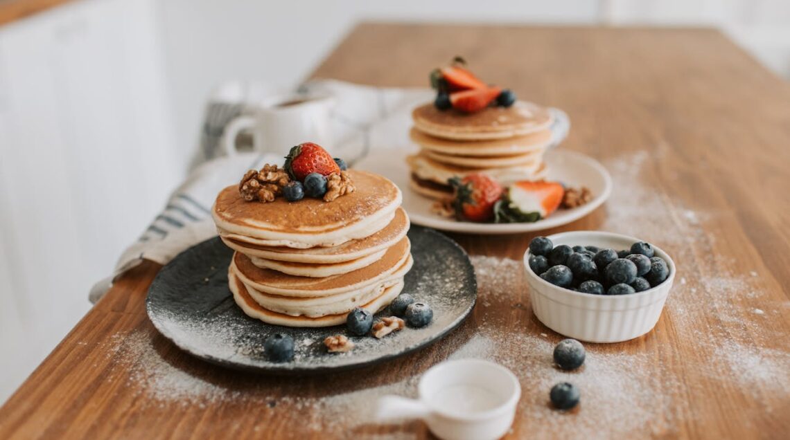 pancakes classici impilati su piatto con topping di frutti di bosco e mirtilli