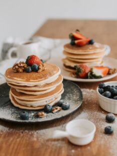 pancakes classici impilati su piatto con topping di frutti di bosco e mirtilli