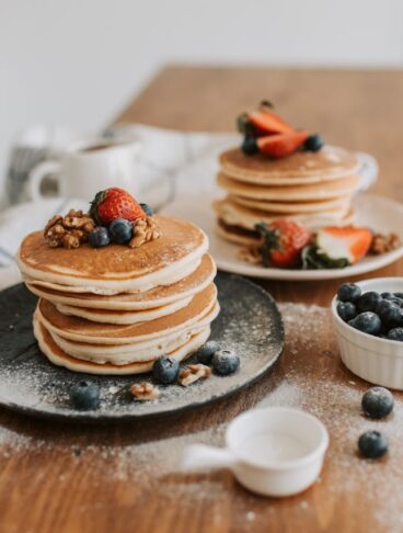 pancakes classici impilati su piatto con topping di frutti di bosco e mirtilli