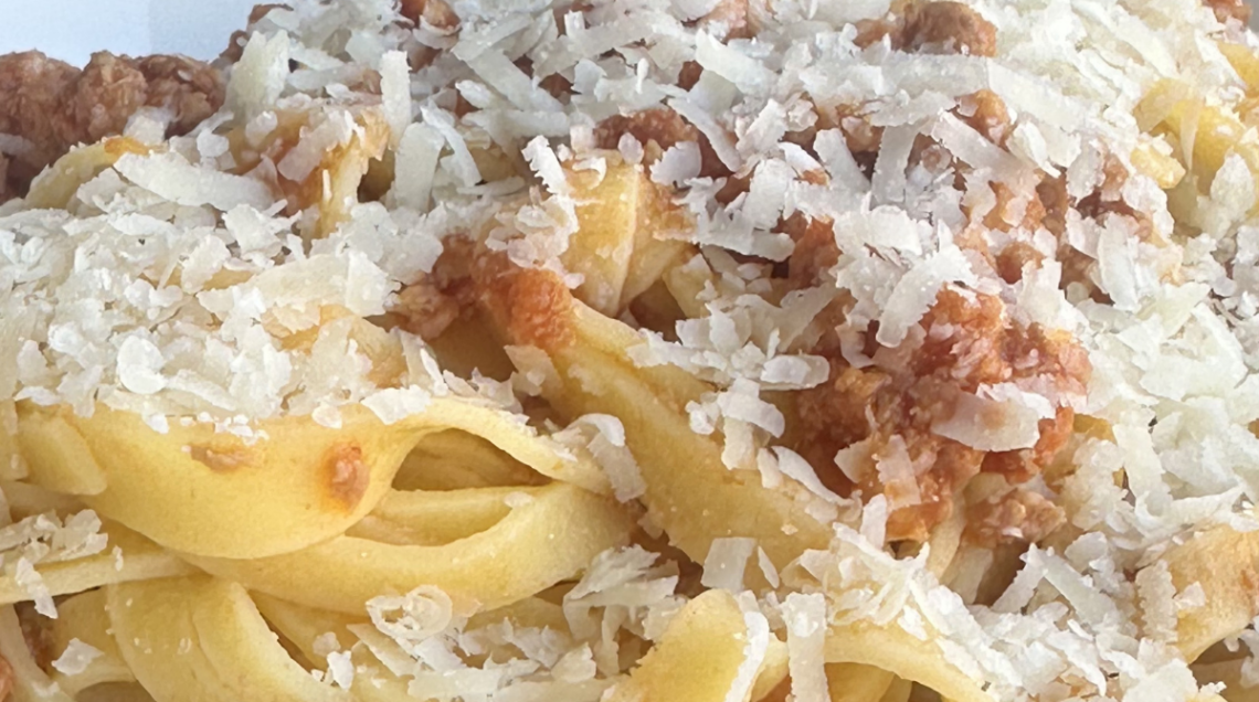 Piatto di pasta fresca lunga lavorata al torchio condita con ragù e abbondante parmigiano reggiano.