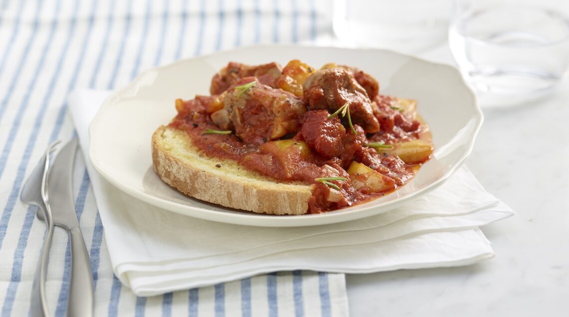 scottiglia di agnello sul pane in un piatto