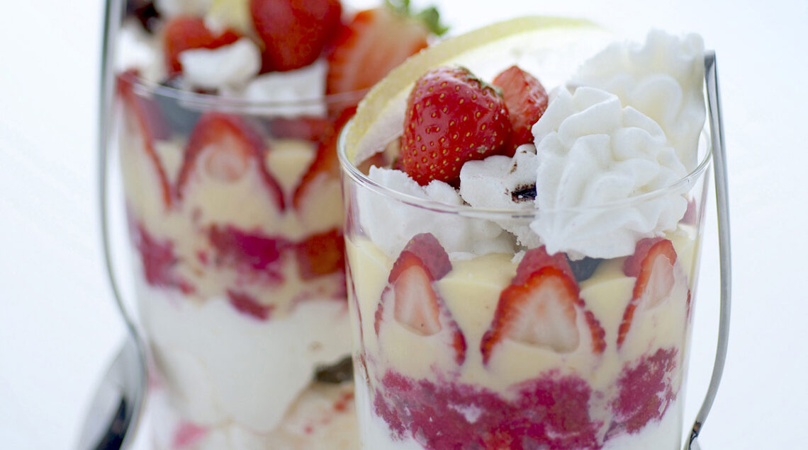 bicchieri con dolce a strati di meringhe, fragole e panna