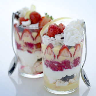 bicchieri con dolce a strati di meringhe, fragole e panna