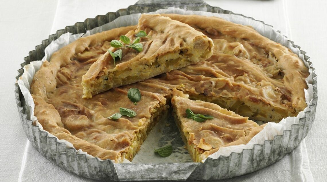 torta salata ligure alle zucchine, disposta in una teglia con una fetta tagliata