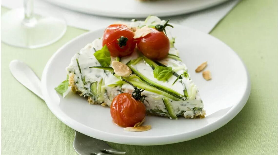 fetta di cheesecake salata ricoperta di zucchine a fette con pomodorini interi
