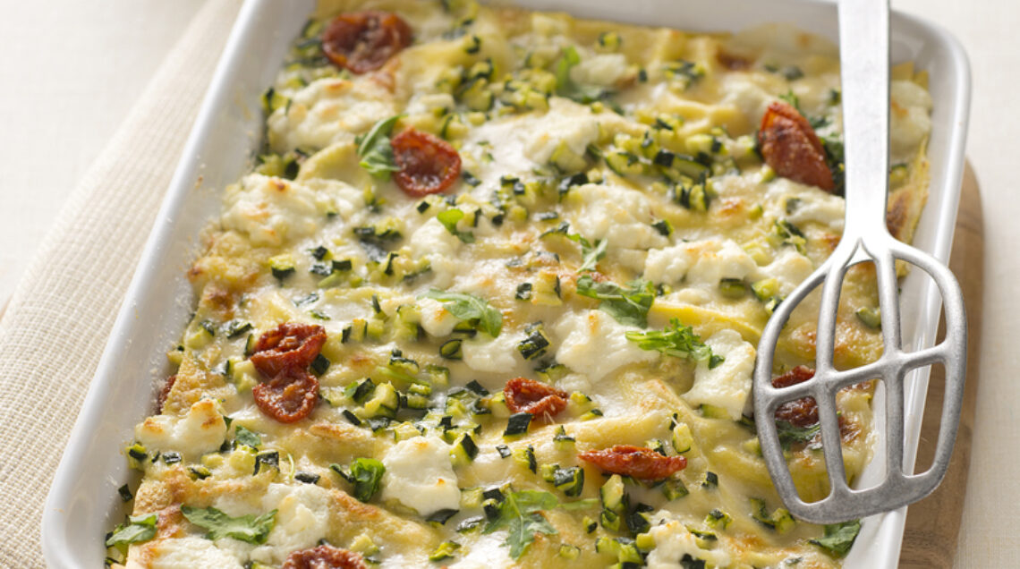 teglia appoggiata su un tavolo di lasagne di zucchine, speck e caprino