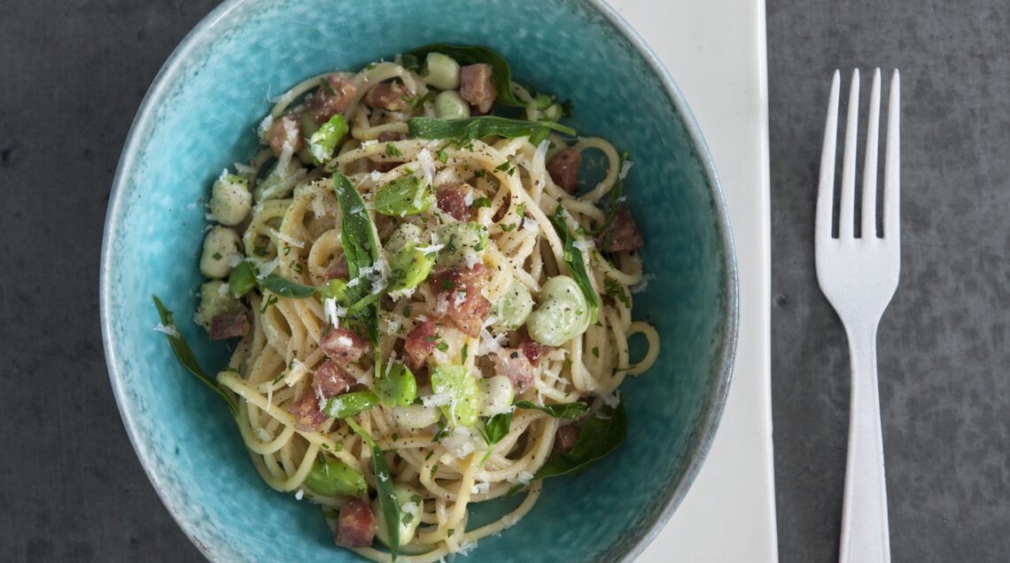 piatto di spaghetti alla carbonara con fave e salame