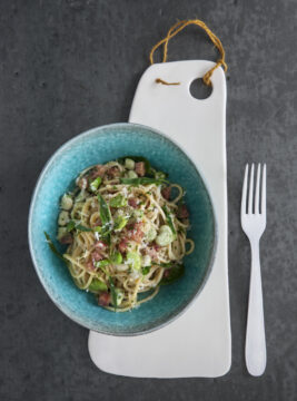 piatto di spaghetti alla carbonara con fave e salame