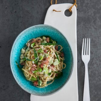 piatto di spaghetti alla carbonara con fave e salame