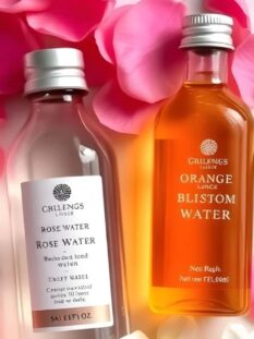 Una boccetta di acqua di rose e una di acqua di fiori d'arancio, in mezzo a tanti petali