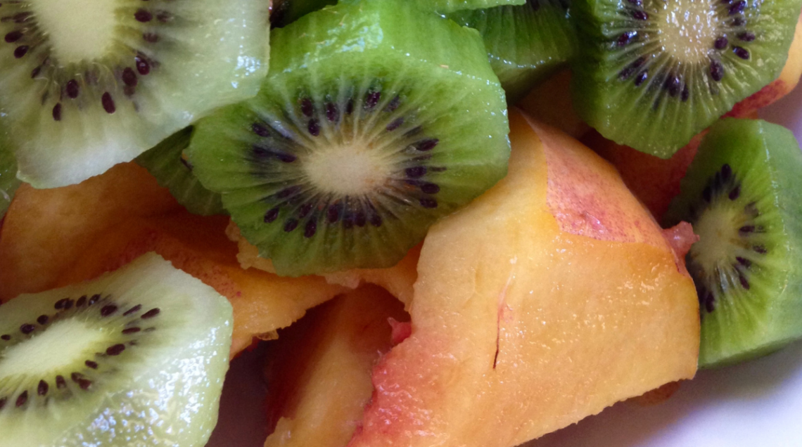 Pezzi di pesca gialla e fette di kiwi fresco pronti per preparare un'acqua aromatizzata alla frutta.