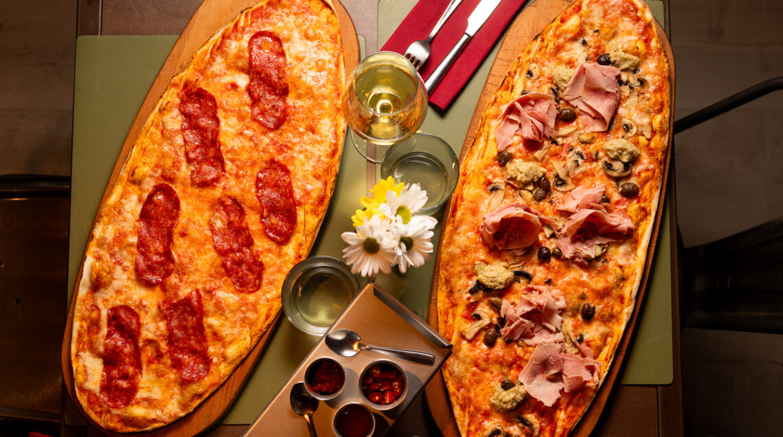 pizza bassa e lunga disposta su vassoi su un tavolo