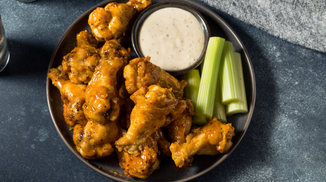 Buffalo Wings,in un piatto con una ciotola di dip di formaggio erborinato e sedano