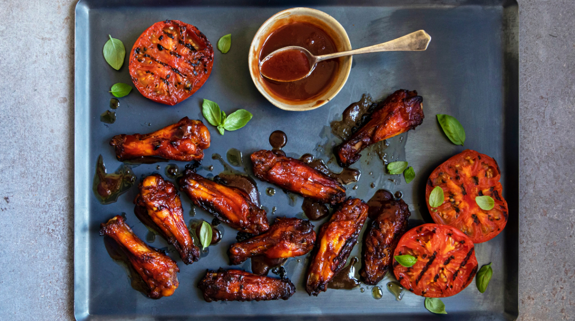 Buffalo wings su una teglia, coperte di salsa piccante al pomodoro, glassate e pronte da gustare