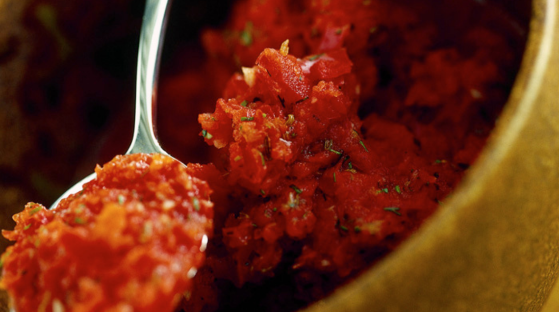 Ciotola con cucchiaio in primo piano con pasta di harissa appena fatta