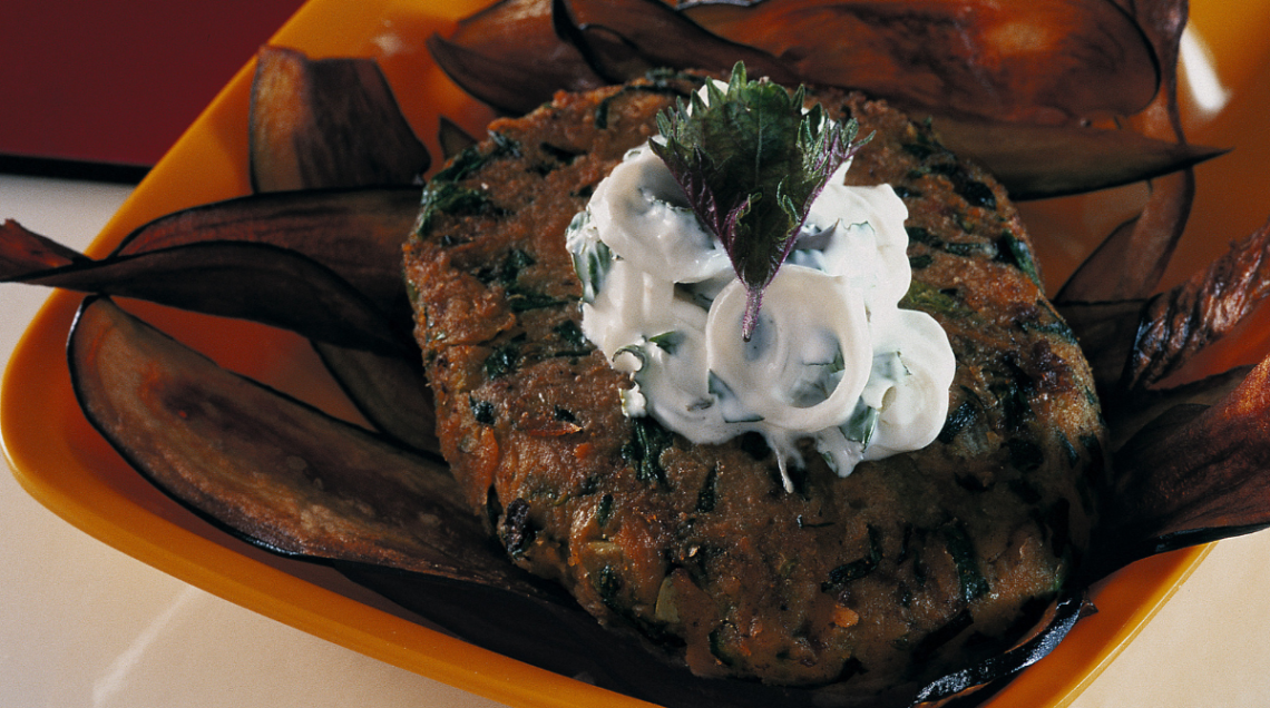 Hamburger vegetariano con salsa di yogurt, in un piatto quadrato e arancione