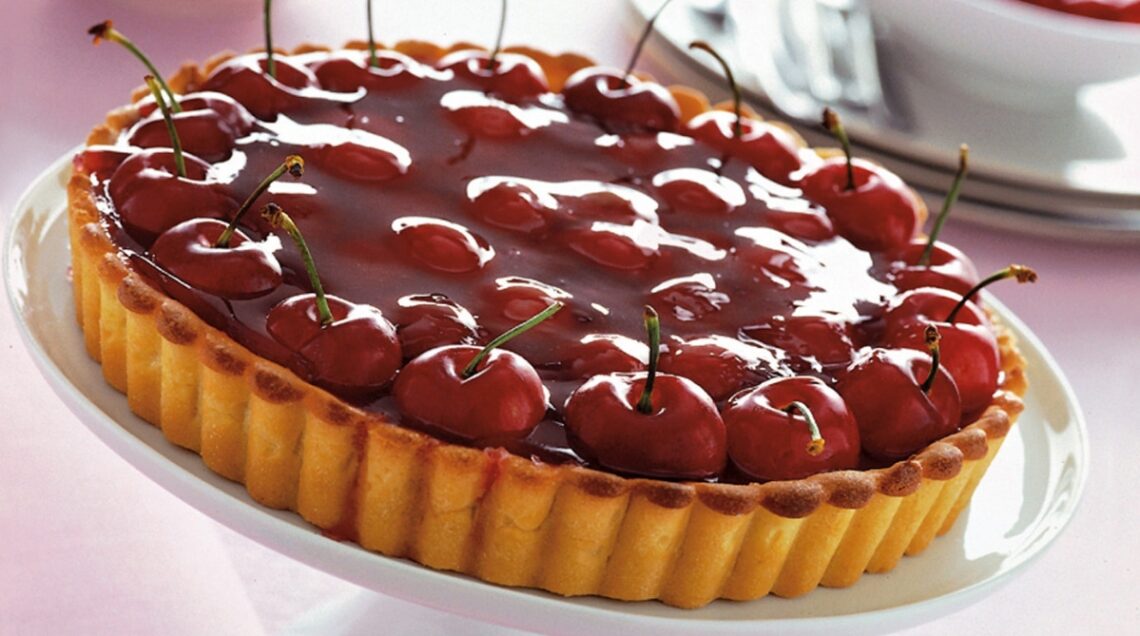 Una grande crostata di ciliegie con base frolla, lucida rossa e accattivante