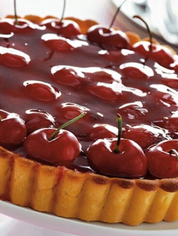 Una grande crostata di ciliegie con base frolla, lucida rossa e accattivante
