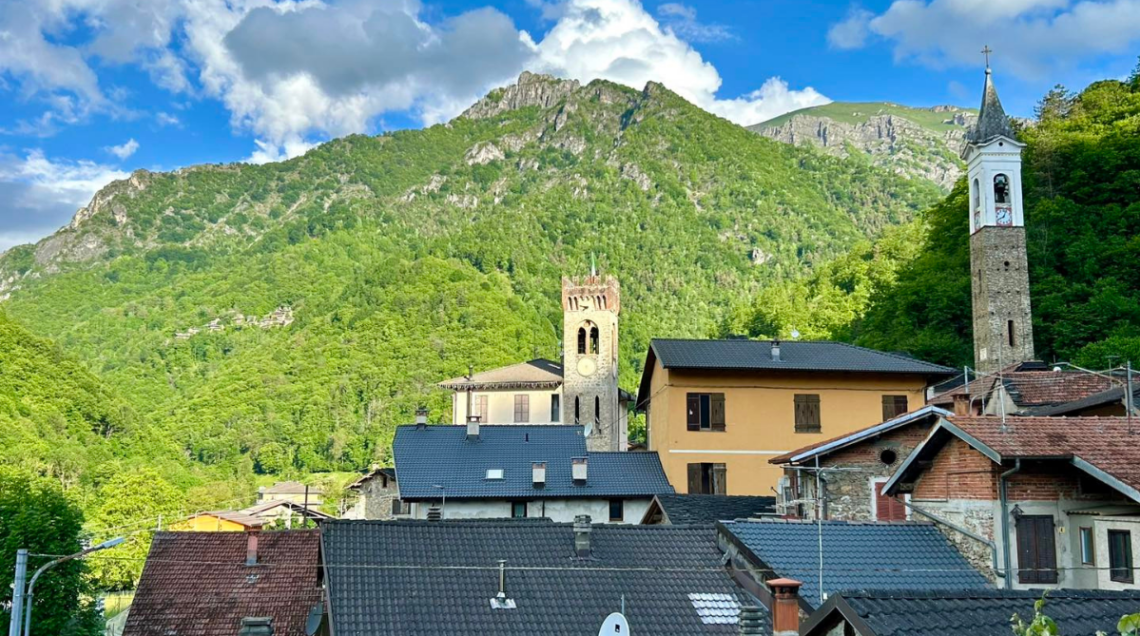 Veduta panoramica di un tipico borgo alpino della Valle Grana con tetti in ardesia e campanile. 