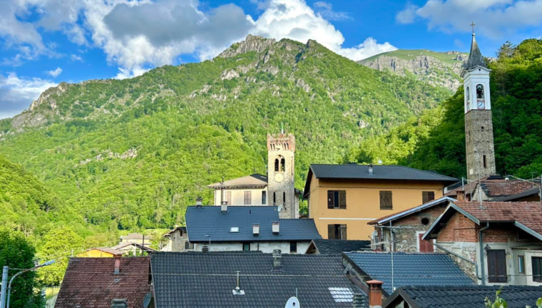 Veduta panoramica di un tipico borgo alpino della Valle Grana con tetti in ardesia e campanile. 