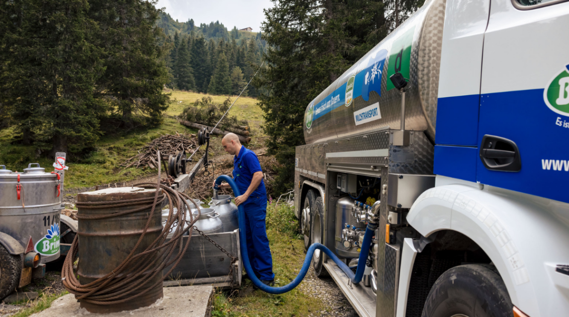 Operatore che collega un tubo a un camion cisterna Brimi per la raccolta del latte in montagna.