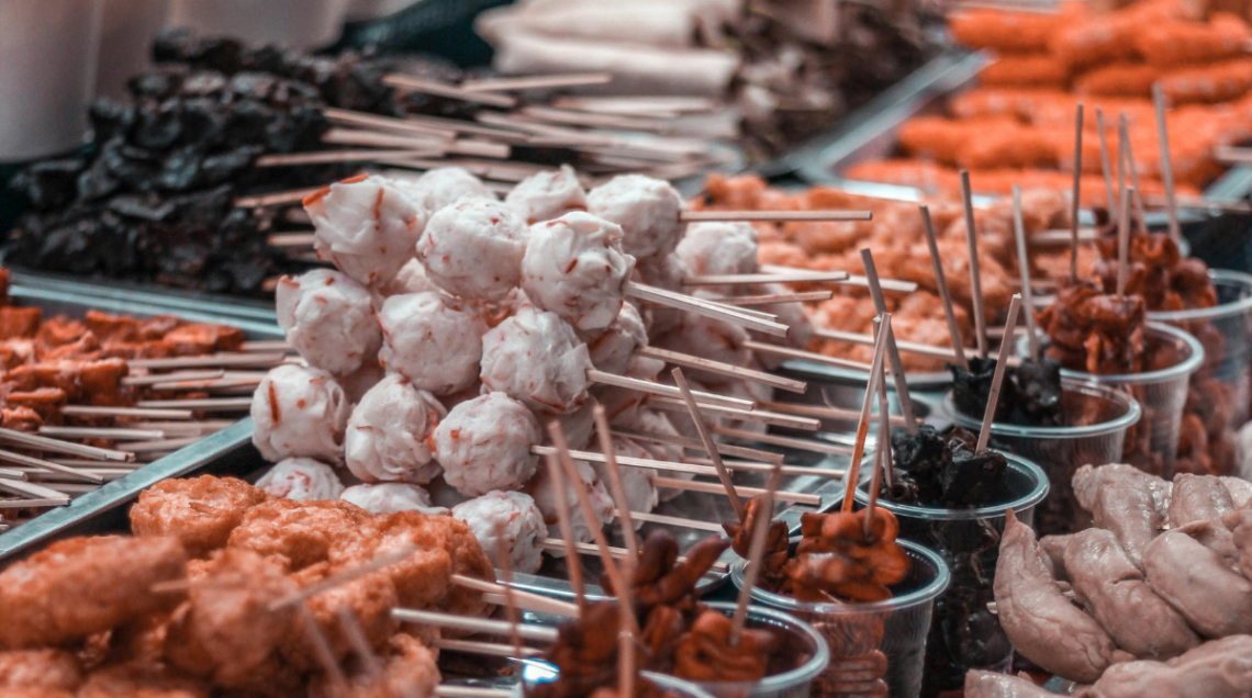 Assortimento di street food filippino su spiedini, inclusi fishball, polpette di carne e spiedini di frattaglie grigliate in un mercato all'aperto. 