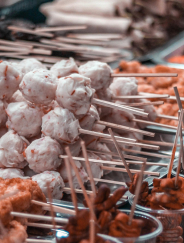Assortimento di street food filippino su spiedini, inclusi fishball, polpette di carne e spiedini di frattaglie grigliate in un mercato all'aperto. 