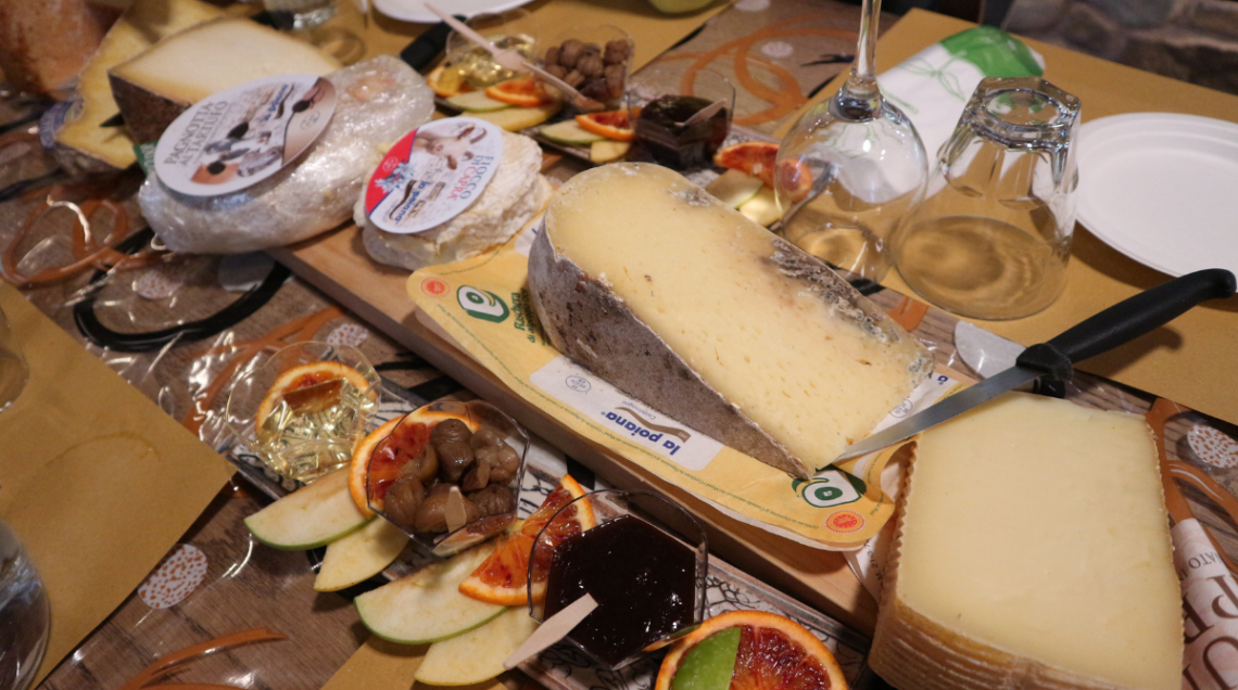 Tagliere con diverse tipologie di formaggio, marmellate e frutta durante una degustazione.