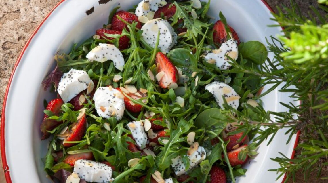 insalata di rucola e fragole e formaggio di capra in una ciotola bianca su un tavolo