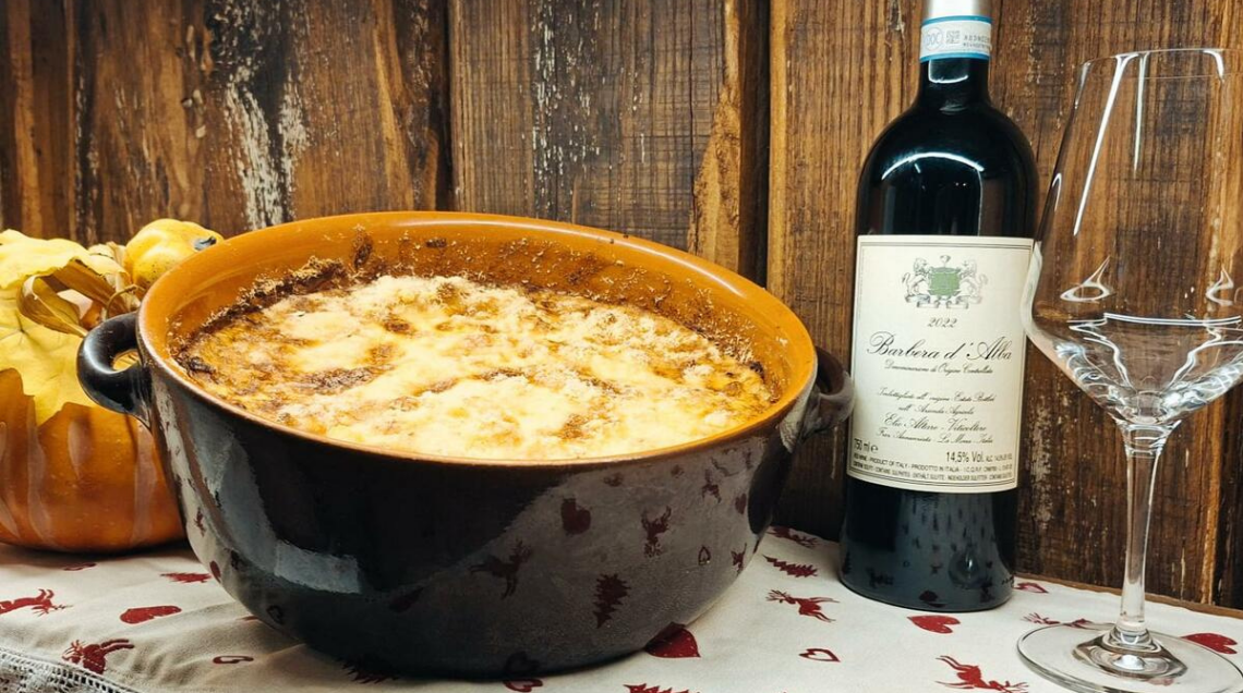 Una teglia di ceramica con gli strati di patate, porri e zucca pronti per essere infornati per la Tourto Mato