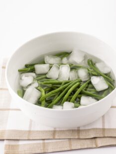 Fagiolini immersi in una ciotola con acqua e ghiaccio